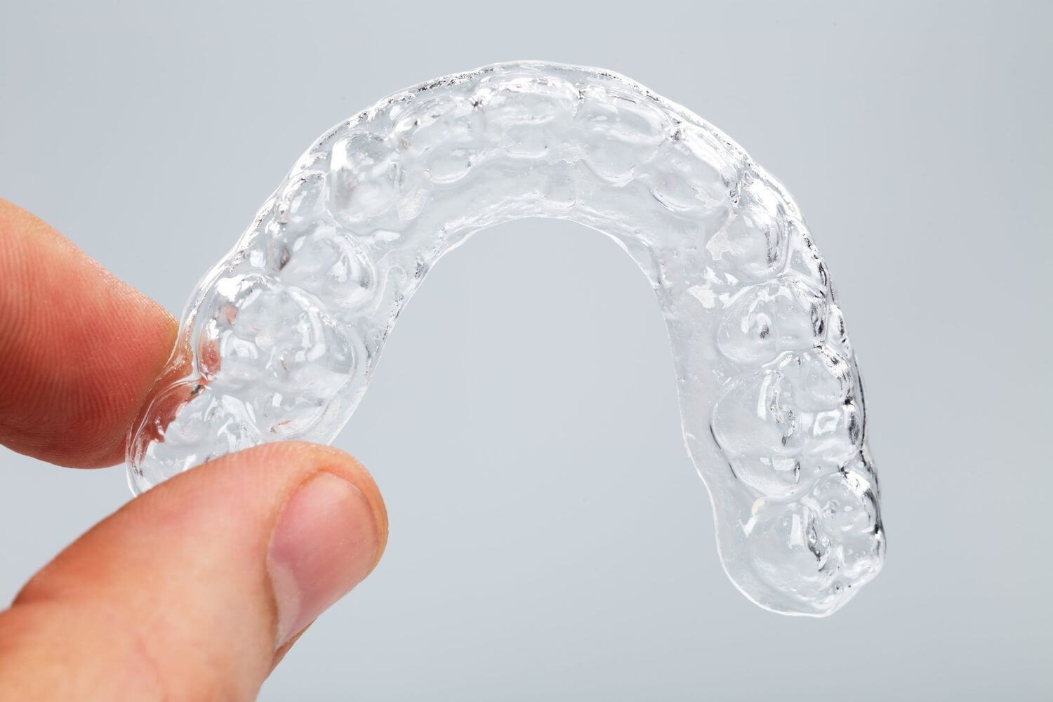 Clear orthodontic aligner held in a hand